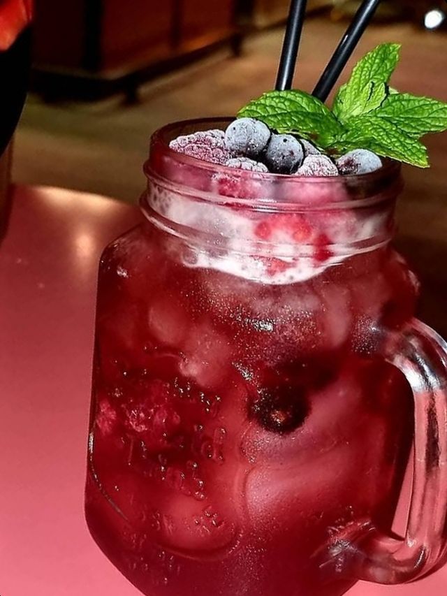 Strawberry cocktail in a jar, topped with berries and mint